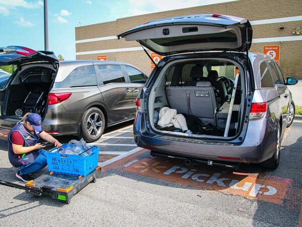 a delivery worker near a car with an open trunk