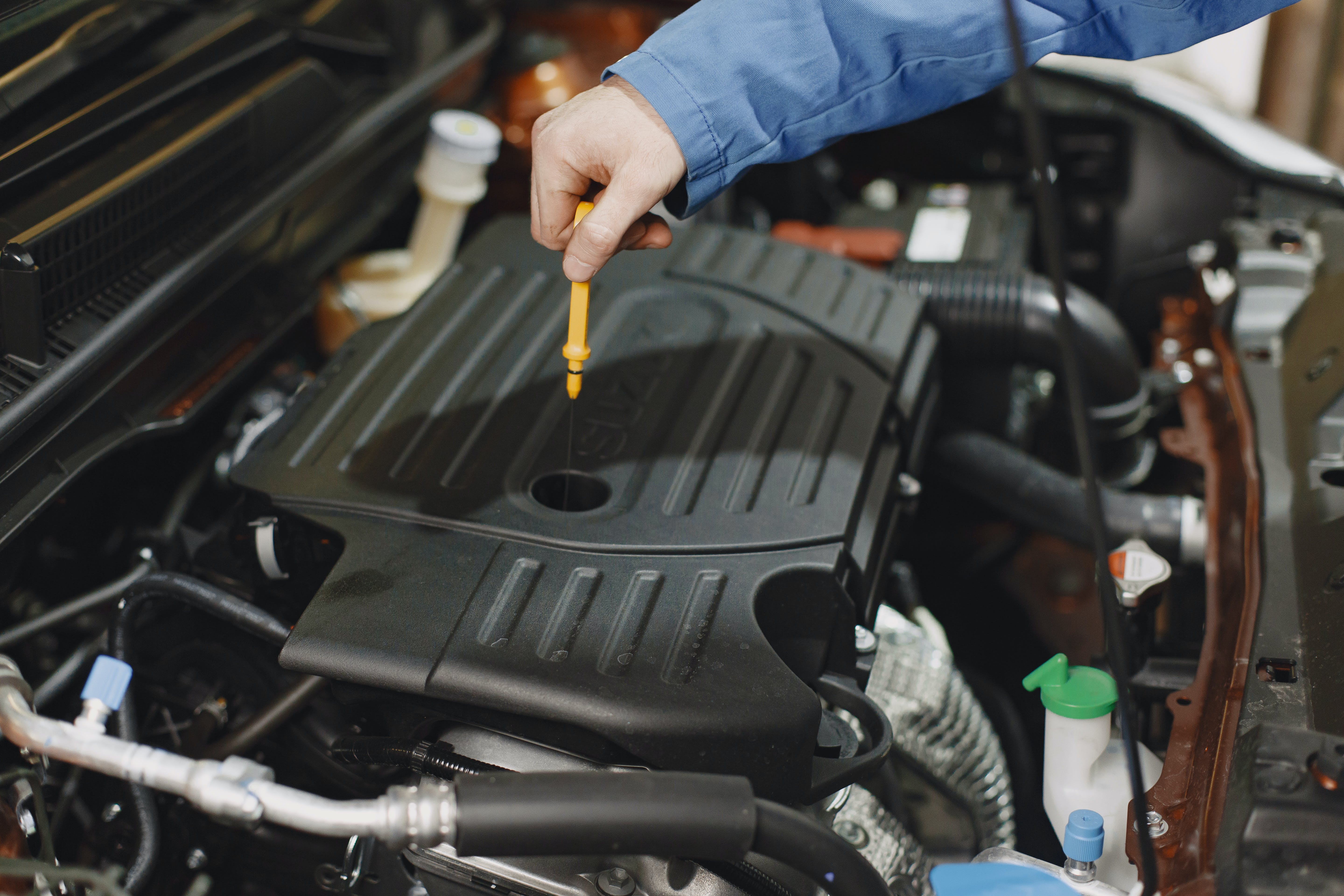 Man checking the oil of a car engine