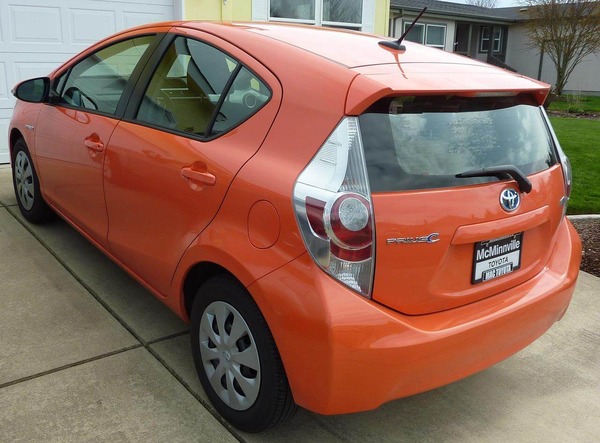 An orange Toyota Prius hatchback sitting in a driveway