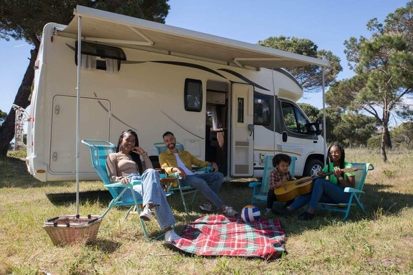 a family sitting next to a camper with its awning extended